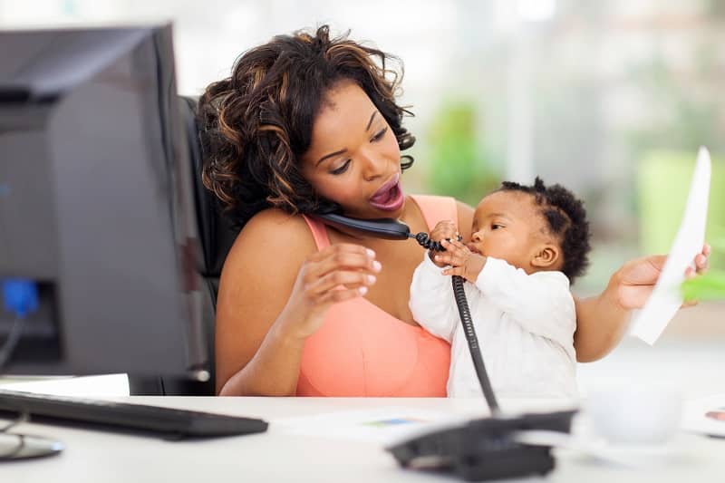 busy african businesswoman with baby girl working in office