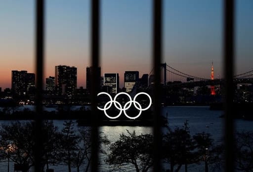 FILE PHOTO: The Olympic rings are pictured at dusk through a steel fence, at the waterfront area of the Odaiba Marine Park, after the postponing of the Olympic Games Tokyo 2020, due to the outbreak of coronavirus disease (COVID 19), in Tokyo, Japan March 25, 2020.   REUTERS/Issei Kato/File Photo