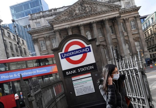 A woman wearing a protective face mask walks out of an underground tube station in the City of London financial district, whilst British stocks tumble as investors fear that the coronavirus outbreak could stall the global economy, London, Britain, March 9, 2020. REUTERS/Toby Melville