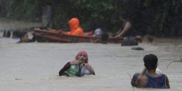 A man uses plastic containers to keep himself afloat as he crosses flooded road in Marikina, Philippines, due to Typhoon Vamco on Thursday, Nov. 12, 2020. The typhoon swelled rivers and flooded low-lying areas as it passed over the storm-battered northeast Philippines, where rescuers were deployed early Thursday to help people flee the rising waters. (AP Photo/Aaron Favila)