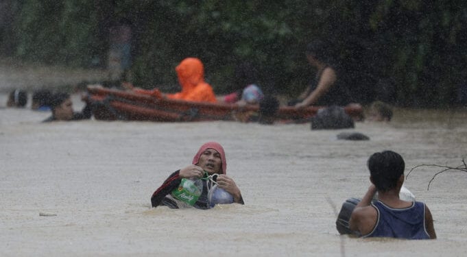 A man uses plastic containers to keep himself afloat as he crosses flooded road in Marikina, Philippines, due to Typhoon Vamco on Thursday, Nov. 12, 2020. The typhoon swelled rivers and flooded low-lying areas as it passed over the storm-battered northeast Philippines, where rescuers were deployed early Thursday to help people flee the rising waters. (AP Photo/Aaron Favila)