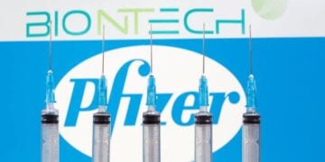 FILE PHOTO: Syringes are seen in front of displayed Biontech and Pfizer logos in this illustration taken November 10, 2020. REUTERS/Dado Ruvic/Illustration/File Photo