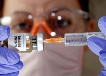 FILE PHOTO: A woman holds a small bottle labeled with a "Vaccine COVID-19" sticker and a medical syringe in this illustration taken April 10, 2020. REUTERS/Dado Ruvic//File Photo