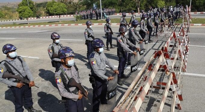 Policemen wearing protective face mask stand guard behind a road barricade, as a part of security preparations ahead of next week's opening of Myanmar's parliament in Naypyitaw, Myanmar, Friday, Jan. 29, 2021. Myanmar's election commission rejected allegations by the military that fraud played a significant role in determining the outcome of November's elections, which delivered a landslide victory to Aung San Suu Kyi's ruling party.(AP Photo/Aung Shine Oo)