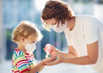 Family with kids in face mask in shopping mall or airport. Mother and child wear facemask during coronavirus and flu outbreak. Virus and illness protection, hand sanitizer in public crowded place.