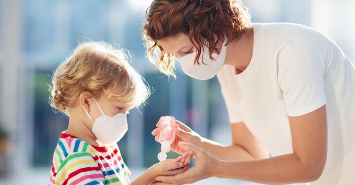 Family with kids in face mask in shopping mall or airport. Mother and child wear facemask during coronavirus and flu outbreak. Virus and illness protection, hand sanitizer in public crowded place.